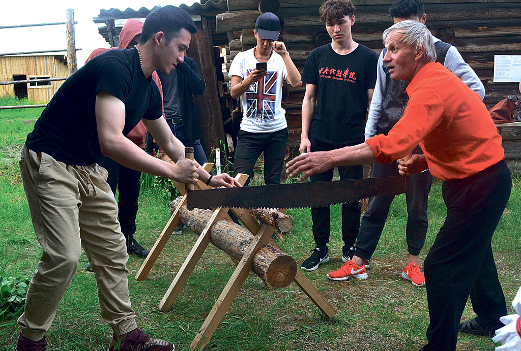 Племянник Федора Абрамова — Владимир Михайлович Абрамов — показывает китайским студентам, как правильно пилить дрова